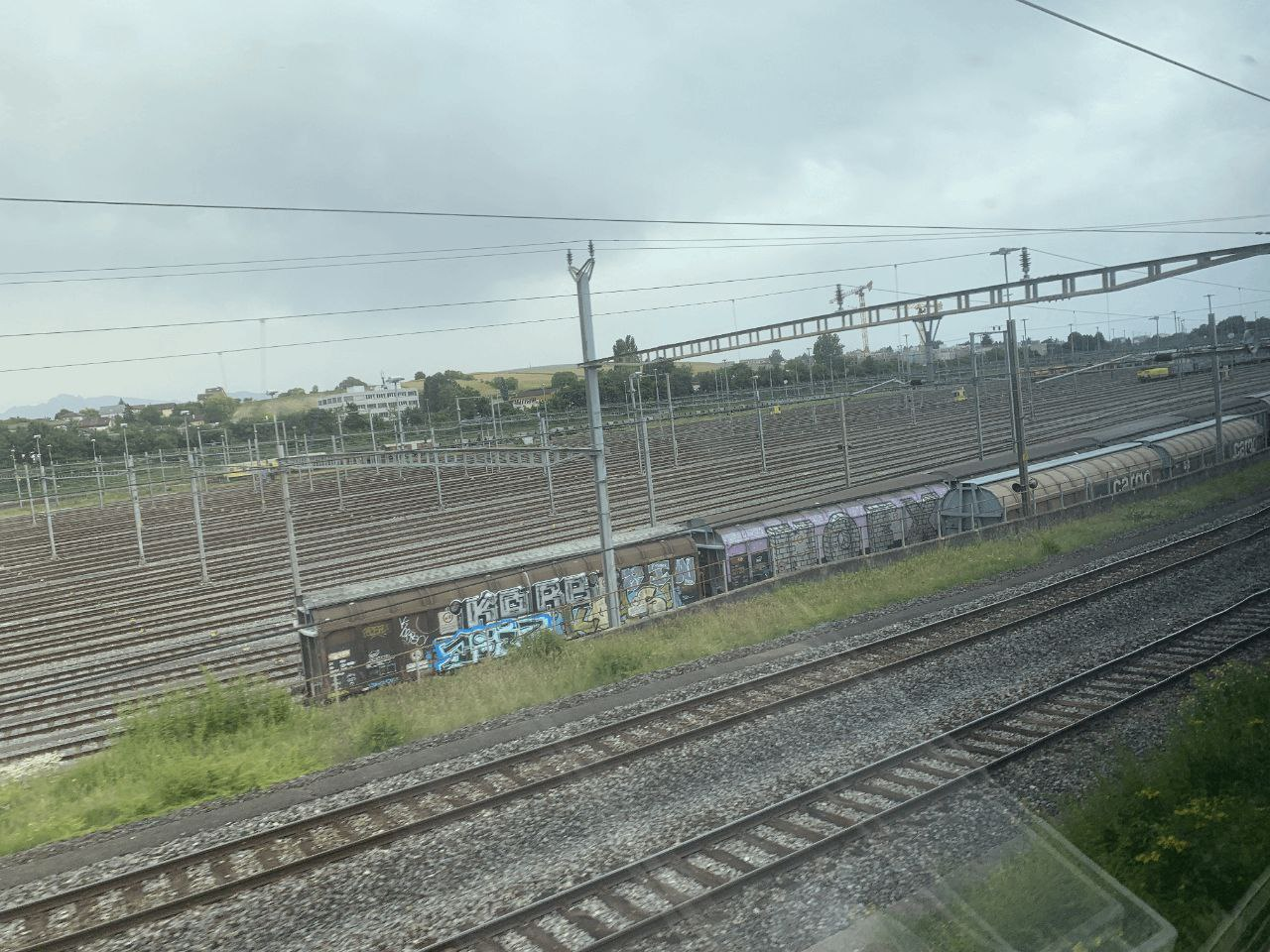 A photo of an enormous rail yard. In the foreground there are two running tracks, in the background like 32 or more (I counted but then the tracks got too small in the distance) yard tracks